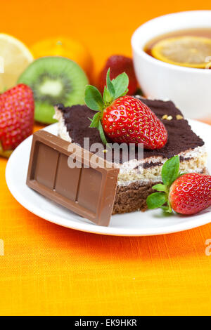 Tee mit Zitrone, Schokolade, Kiwi, Kuchen und Erdbeeren auf der Ora liegend Stockfoto