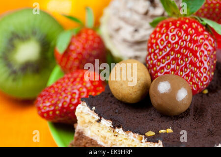 Kuchen, Pralinen, Mandarine, Kiwi und Erdbeeren auf der o Stockfoto