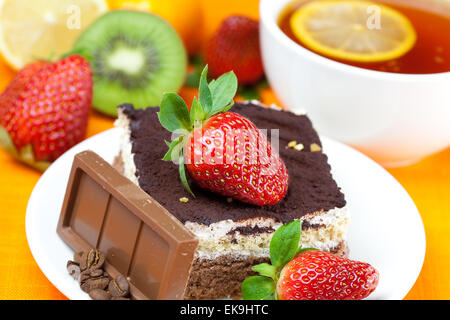 Tee mit Zitrone, Schokolade, Kiwi, Kuchen und Erdbeeren auf der Ora liegend Stockfoto