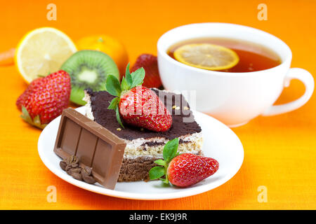 Tee mit Zitrone, Schokolade, Kiwi, Kuchen und Erdbeeren auf der Ora liegend Stockfoto