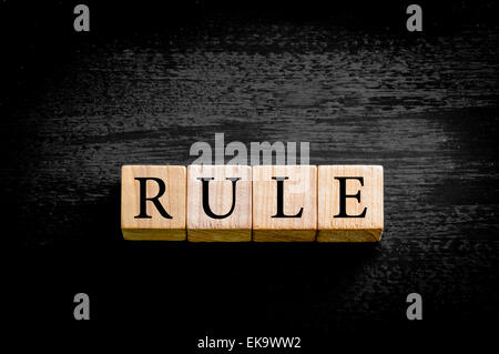 Wort Regel. Hölzerne kleine Würfel mit Buchstaben auf schwarzem Hintergrund mit Kopie Speicherplatz isoliert. Konzept-Bild. Stockfoto