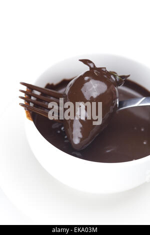 geschmolzene Schokolade in eine Tasse, Gabel und Erdbeeren isoliert auf whi Stockfoto