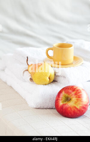 Tasse Tee, Apfel und Birne auf dem Bett Stockfoto