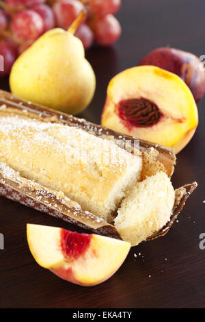 Pfirsich, Birne, Pflaume, Kokos-Kuchen und Trauben auf einem Holztisch Stockfoto