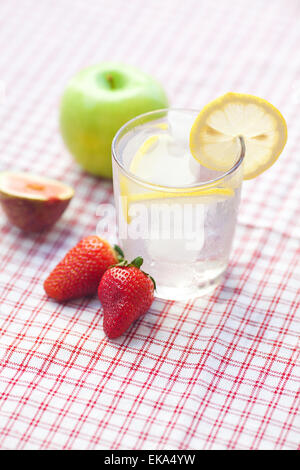 Cocktail mit Eis, Zitrone, Apfel, Feigen und Erdbeeren auf einem Teller Stockfoto