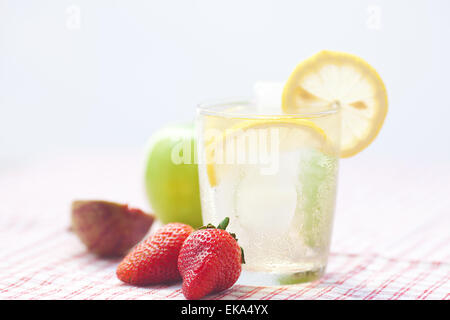 Cocktail mit Eis, Zitrone, Apfel, Feigen und Erdbeeren auf einem Teller Stockfoto