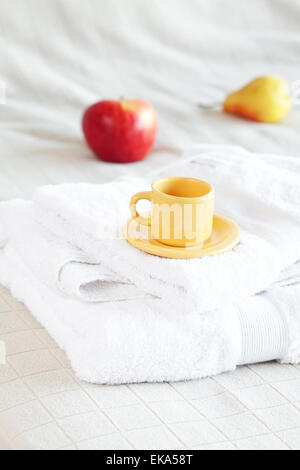 Tasse Tee, Apfel und Birne auf dem Bett Stockfoto