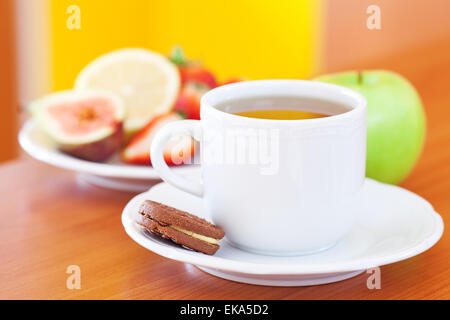 Tasse Tee, Cookie, Apfel, Zitrone, Feigen und Erdbeeren auf einem Teller Stockfoto