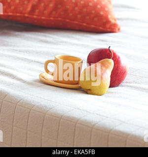 Tasse Tee, Apfel und Birne auf dem Bett Stockfoto