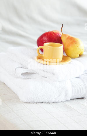 Tasse Tee, Apfel und Birne auf dem Bett Stockfoto