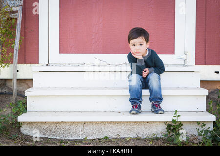 Süße Mischlinge Junge sitzt entspannt auf den Stufen auf einer Scheune. Stockfoto