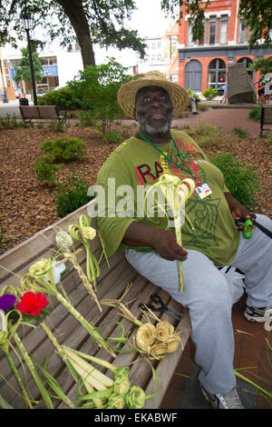 Afrikanische amerikanischer Mann verkaufen Fluss Straße Rosen gewebt aus Palmwedeln in Savannah, Georgia, USA. Stockfoto