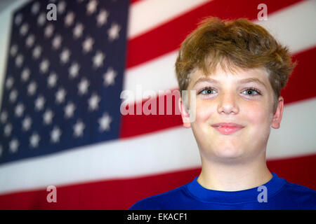 Zehn Jahre alte amerikanische junge steht vor einer amerikanischen Flagge in Charleston, South Carolina, USA. HERR Stockfoto