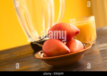 Tamarillo Früchte (lat. Solanum Betaceum) in Schüssel mit Tamarillo Saft und Mixer in den Rücken Stockfoto