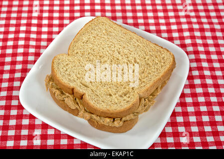 Peanut Butter Sandwich auf Vollkornbrot auf einem quadratischen weißen Teller. Stockfoto