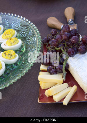 Deviled Eiern serviert mit Gouda und Brie-Käse, garniert mit schwarzen Trauben Stockfoto