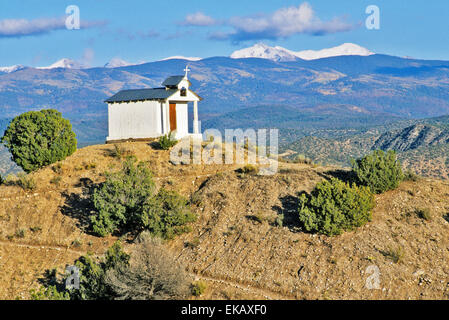 Eingerahmt von den entfernten schneebedeckten Sangre de Cristo Mountains, die winzigen Santa Rita Chapel steht auf einem Hügel. Stockfoto