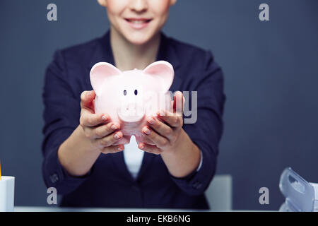 Weibliche Hände halten Sparschwein Stockfoto