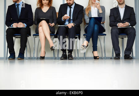 Linie junge Leute sitzen durch die Wand während des Wartens auf ihre Wendung zum interview Stockfoto