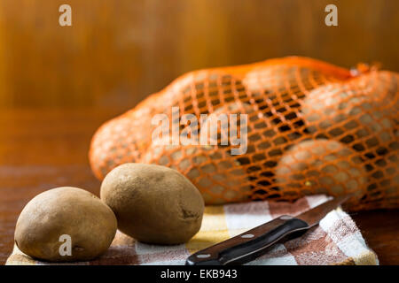 Frisch geerntete Kartoffeln auf einem groben Holztisch mit einem Messer Stockfoto