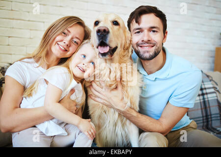 Moderne Familie mit Hund, Blick in die Kamera während der Heimat rest Stockfoto