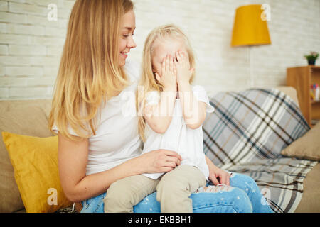 Kleines Mädchen auf ihre Mutter Knien schließen ihre Augen von Palmen Stockfoto