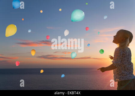 Mädchen beobachten Ballons schweben im Abendhimmel Stockfoto