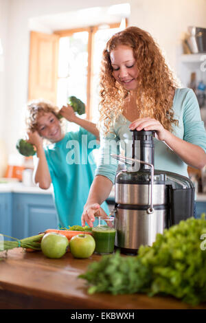 Schwester mischen Obst, Bruder spielt mit Brokkoli im Hintergrund Stockfoto