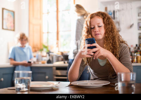 Teenager-Mädchen mit Smartphone am Esstisch Stockfoto