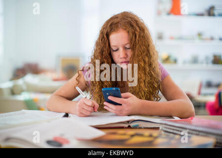 Teenager-Mädchen Schreiben von Notizen und mit smartphone Stockfoto