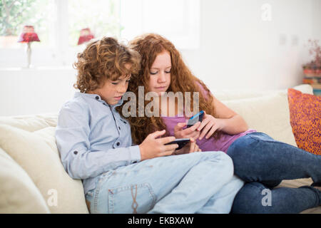 Geschwister spielen mit Handheld-Computer-Spiel auf couch Stockfoto