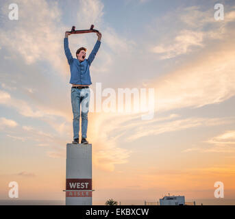 Porträt des jungen Mann auf Säule Skateboard über Kopf halten Stockfoto