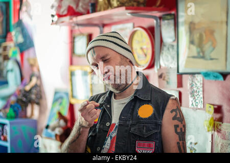 Porträt von männlichen Punk-Ladenbesitzer Zwinkern in Vintage Spielzeug-shop Stockfoto