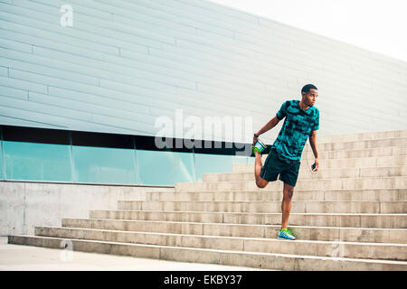 Junge männliche Läufer stretching auf Stadt-Schritte Stockfoto