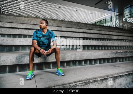 Junge männliche Läufer sitzen auf Stadt-Stufen Stockfoto