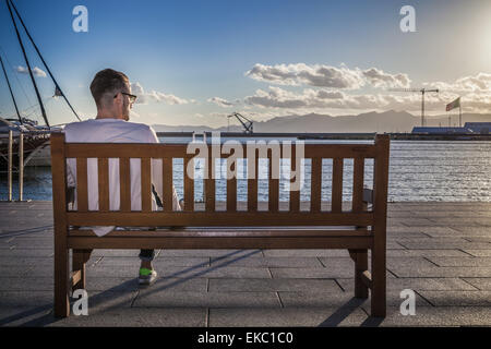 Junger Mann auf Bank von Hafen, Cagliari, Sardinien, Italien Stockfoto