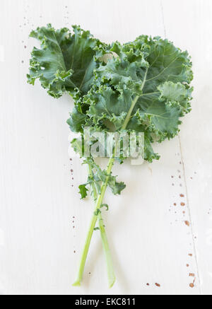 Grünkohl lässt auf eine Creme farbigen hölzernen Hintergrund. Stockfoto