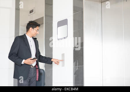 Junge indische Geschäftsmann drücken auf Fahrstuhlknopf, Tür öffnen, geben in der Kabine warten. Stockfoto