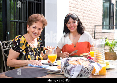 Ein senior hispanic Frau frühstücken im Freien mit einer Tochter. Außengastronomie im Sommer. Ältere Frau im Mittelpunkt. Stockfoto