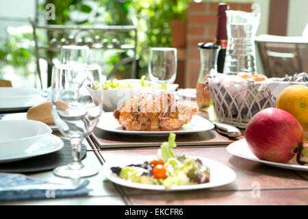 Eine Mahlzeit im Freien speisen komplett mit Brathähnchen, Salat, Brötchen, Wein und Obst im Sommer. Konzept im Freien speisen. Stockfoto