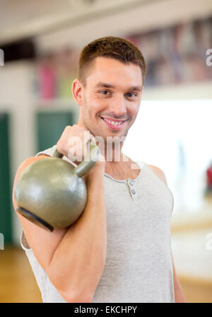 lächelnder Mann mit Kettlebell in Turnhalle Stockfoto