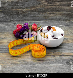 Zentimeter und Müsli mit Joghurt auf rustikalen hölzernen Hintergrund. Stockfoto