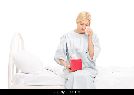 Studio Aufnahme eine traurige Patientin in ein Krankenhaus Kleid Weinen sitzen in einem Krankenhausbett isoliert auf weißem Hintergrund Stockfoto