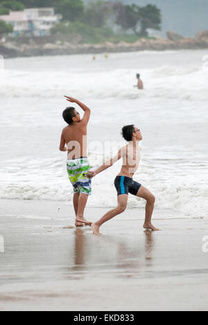 Zwei Jungs spielen am Rande der Brandung am Strand Stockfoto