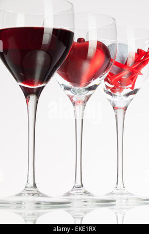 Weingläser mit roten Wein, Herz und Golf Ball auf weißen Tisch Stockfoto