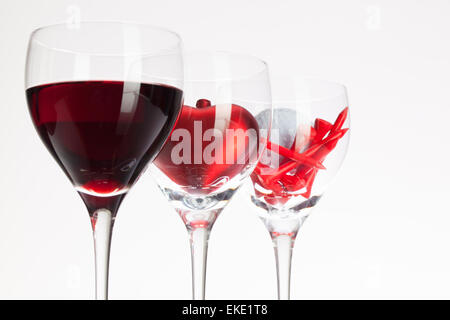 Weingläser mit roten Wein, Herz und Golf Ball auf weißen Tisch Stockfoto