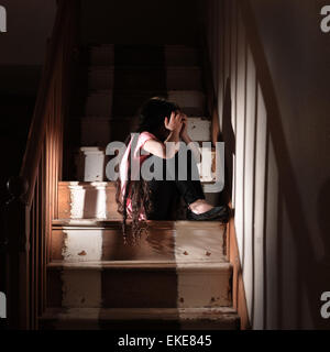 Ein kleines Kind auf der Treppe zu Hause nach Missbrauch leiden. Gestellt von einem Modell Stockfoto