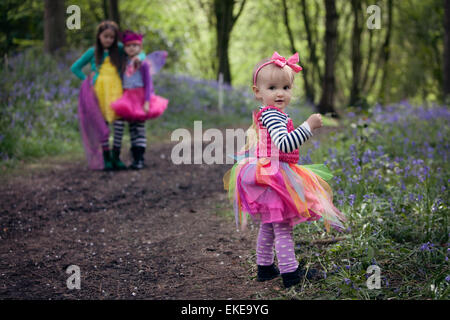 Drei Kinder auf einem Waldweg, umgeben von Glockenblumen, im Frühling. Stockfoto