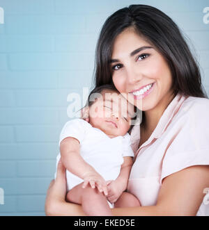 Porträt von glücklich lächelnde Mutter mit süß schlafenden Baby auf Händen, Zeit zu Hause verbringen, liebende Familienkonzept Stockfoto