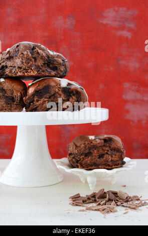 Schokolade Obst Brötchen auf weißen Kuchen stehen auf weißen shabby chic Holztisch mit roten Hintergrund Hintergrund. Stockfoto